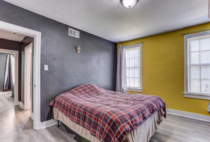 Bedroom featuring a textured wall, light wood-style flooring, and a textured ceiling