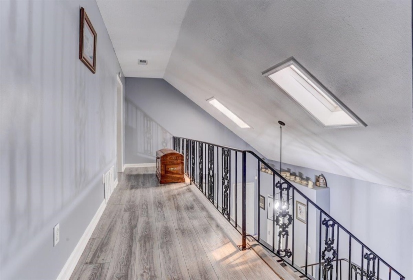 Additional living space featuring lofted ceiling, wood finished floors, a skylight, and a textured ceiling