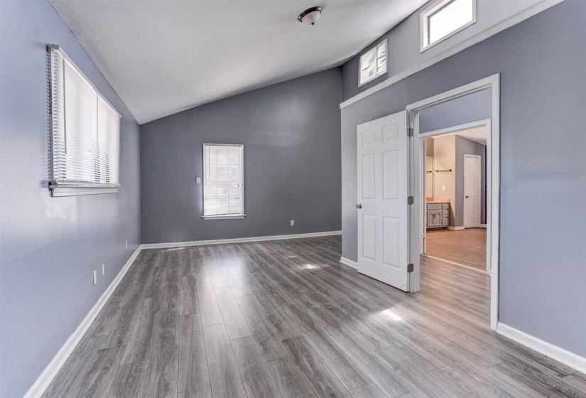 Unfurnished bedroom with wood finished floors and high vaulted ceiling