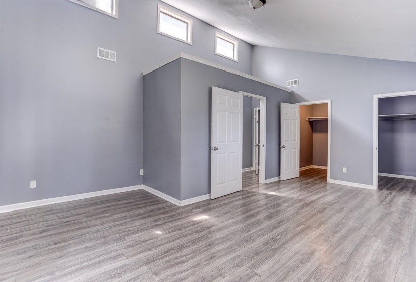 Unfurnished bedroom featuring high vaulted ceiling, a spacious closet, and wood finished floors
