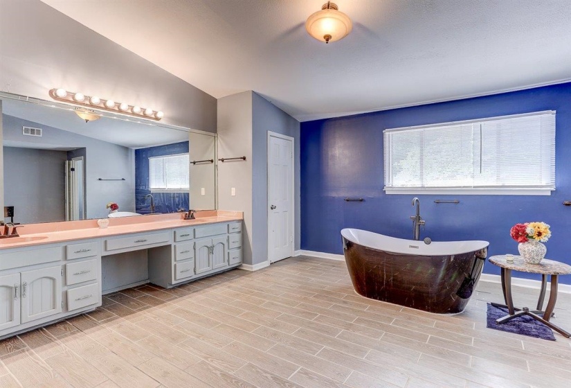 Full bathroom featuring a freestanding tub, double vanity, and wood finish floors
