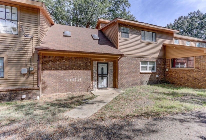 View of front of property featuring brick siding, a front lawn, and roof with shingles