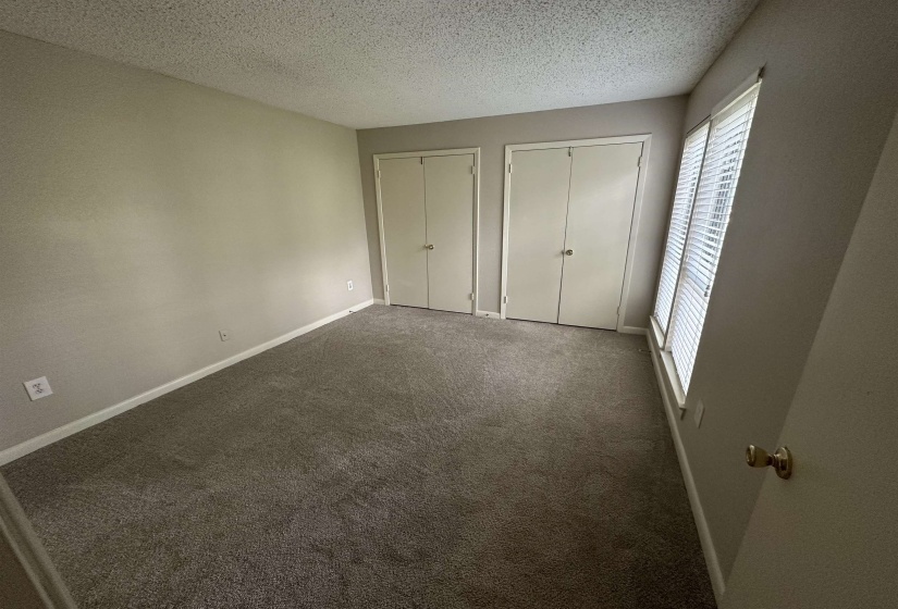 Unfurnished bedroom with multiple closets, carpet floors, and a textured ceiling