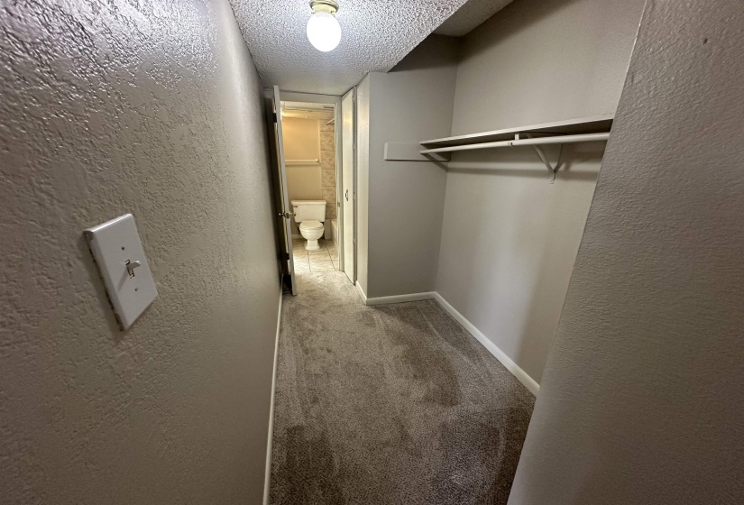 Hallway featuring light colored carpet, a textured wall, and a textured ceiling