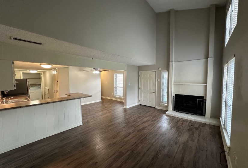 Unfurnished living room featuring dark wood-style flooring, ceiling fan, a large fireplace, a towering ceiling, and washer / clothes dryer