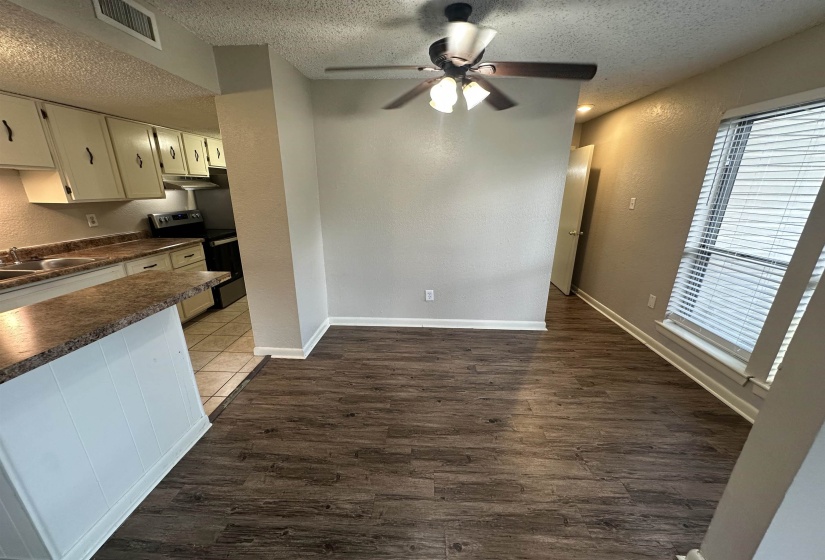 Unfurnished dining area featuring a textured wall, dark wood finished floors, a textured ceiling, and a ceiling fan
