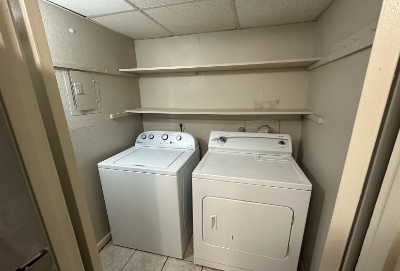Laundry room featuring light tile patterned flooring, independent washer and dryer, and a textured wall