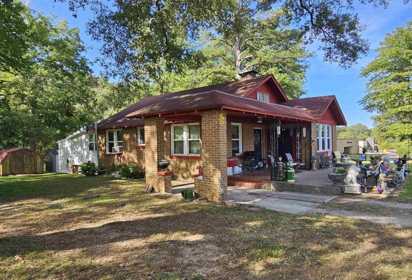 View of front of property with a storage unit, covered porch, brick siding, and a front lawn