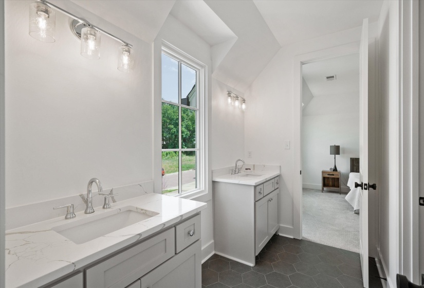 Full bathroom featuring two vanities, dark tile patterned floors, and vaulted ceiling for bedrooms 3 & 4