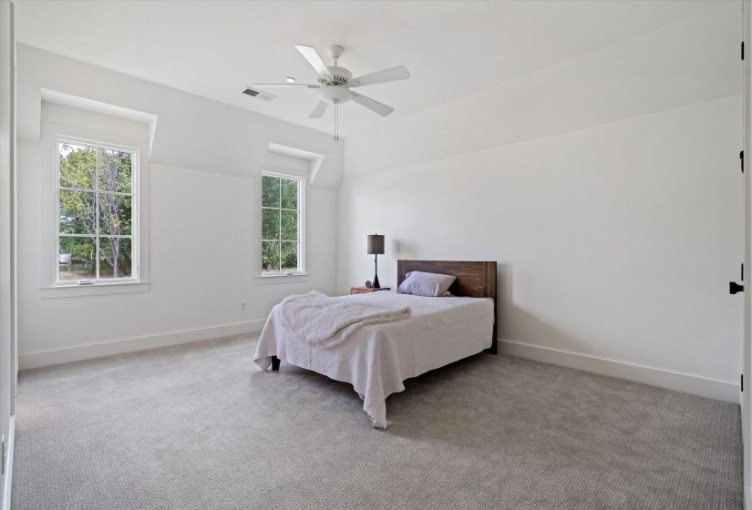 Bedroom with light carpet, multiple windows, ceiling fan, and lofted ceiling