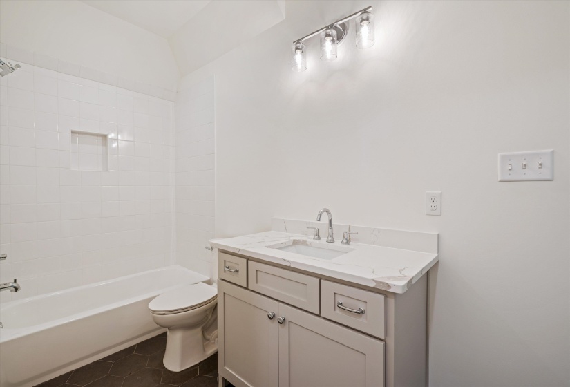Bathroom featuring dark tile patterned flooring, vanity, and shower / washtub combination