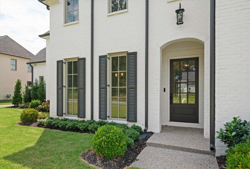 Doorway to property with brick siding and a lawn