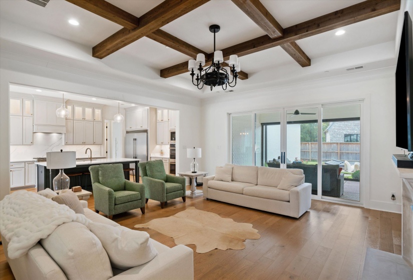Living room featuring a chandelier, light wood-style flooring, beamed ceiling, recessed lighting, and coffered ceiling