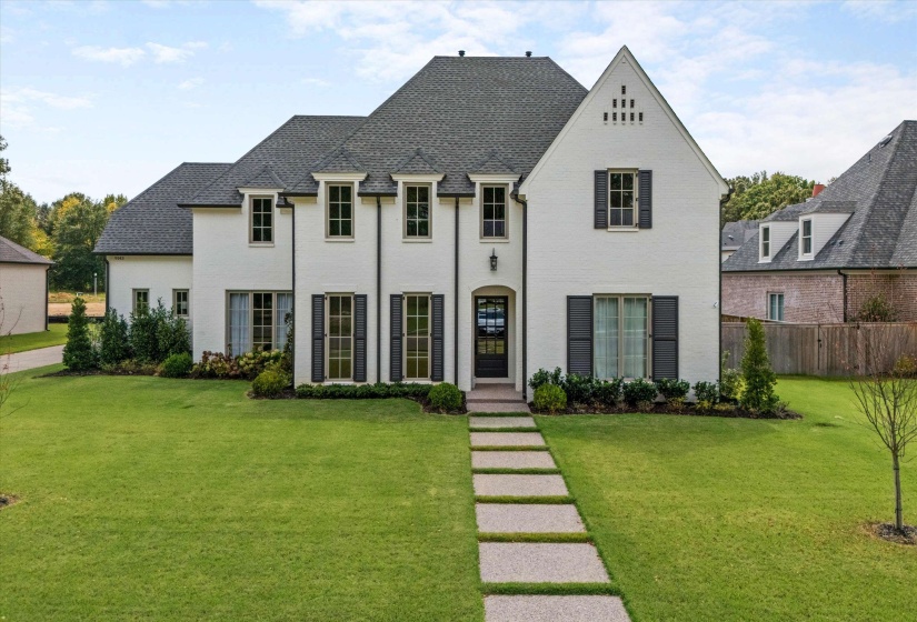 French country inspired facade with brick siding and a shingled roof