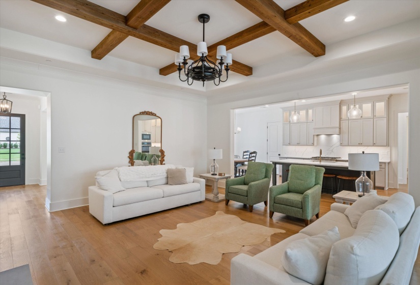 Living room with a chandelier, light wood-type flooring, beam ceiling, coffered ceiling, and recessed lighting