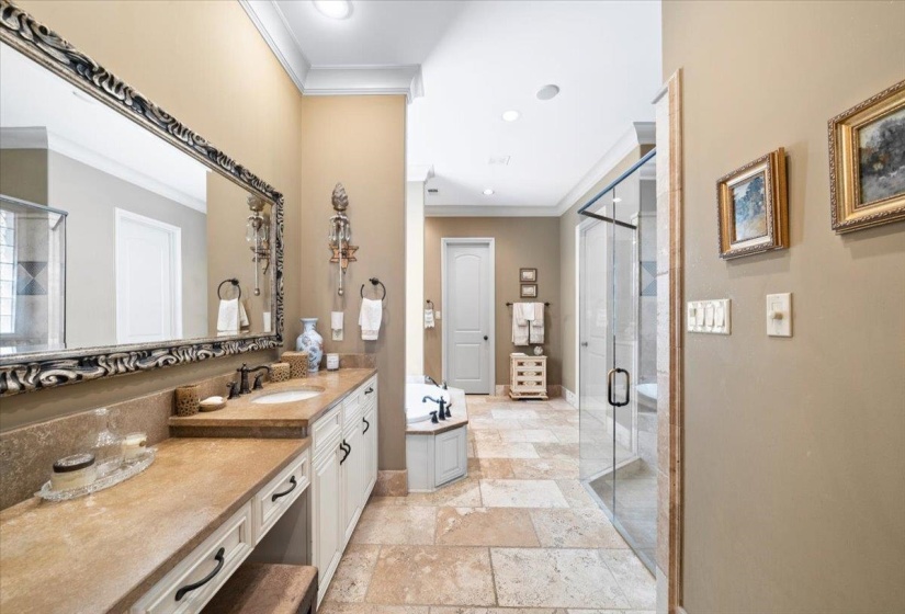 Bathroom featuring vanity, a shower stall, a garden tub, crown molding, and stone tile flooring