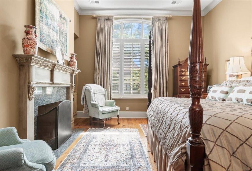 Bedroom with wood finished floors, crown molding, and a high end fireplace