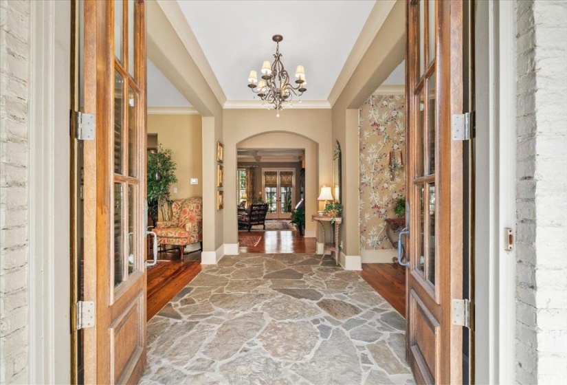 Entrance foyer with french doors, arched walkways, wood finished floors, a chandelier, and ornamental molding