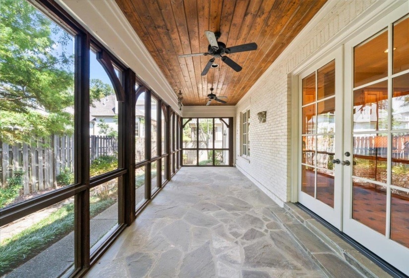 Unfurnished sunroom with stone floors, wooden ceiling, brick wall, french doors, and a ceiling fan