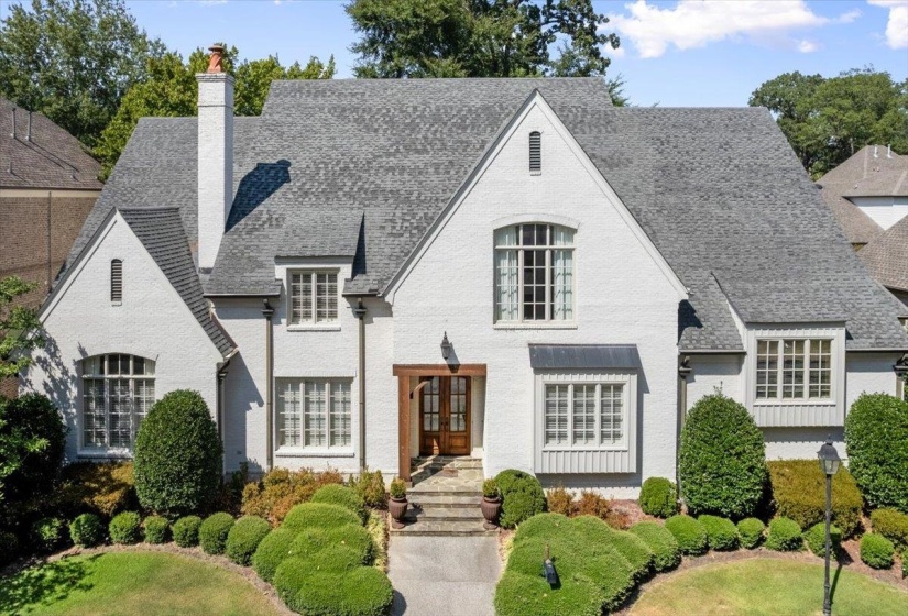 View of front of house featuring a chimney and brick siding