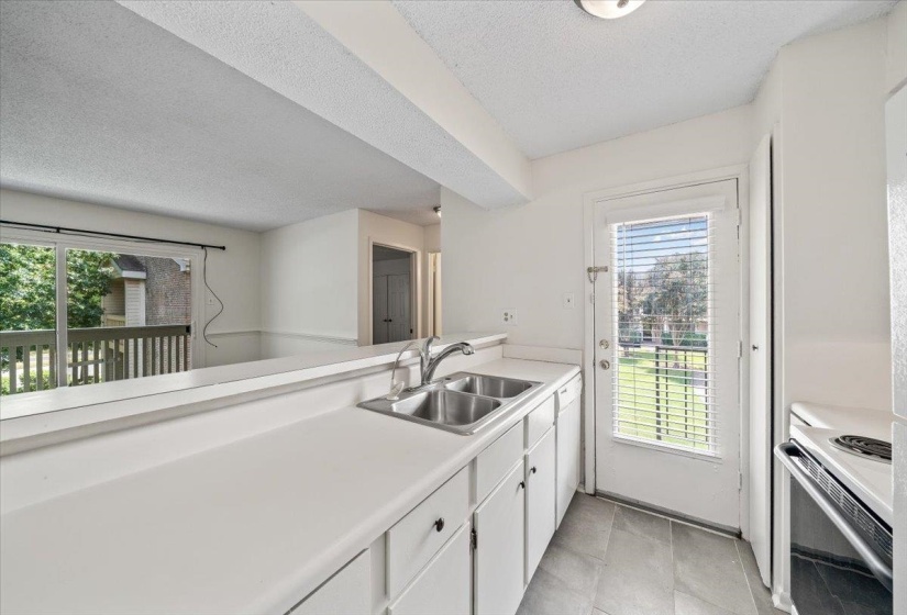 Kitchen featuring light countertops, white cabinets, white appliances, a textured ceiling, and light tile patterned flooring