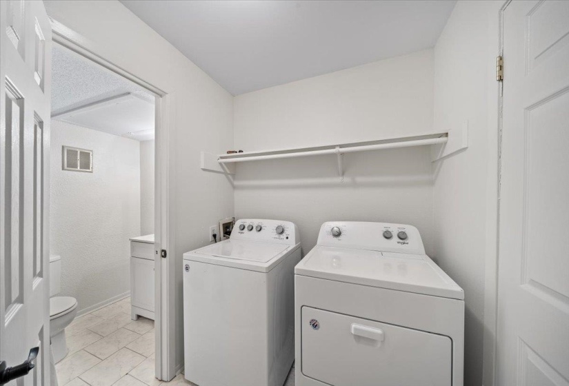 Washroom with washing machine and clothes dryer and light tile patterned flooring