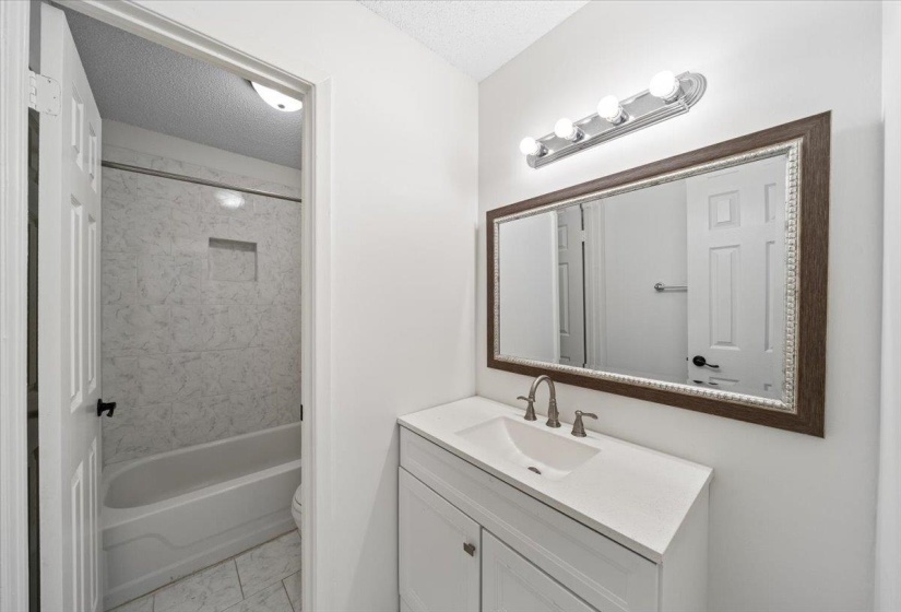Full bath featuring a textured ceiling, vanity, and shower / tub combination