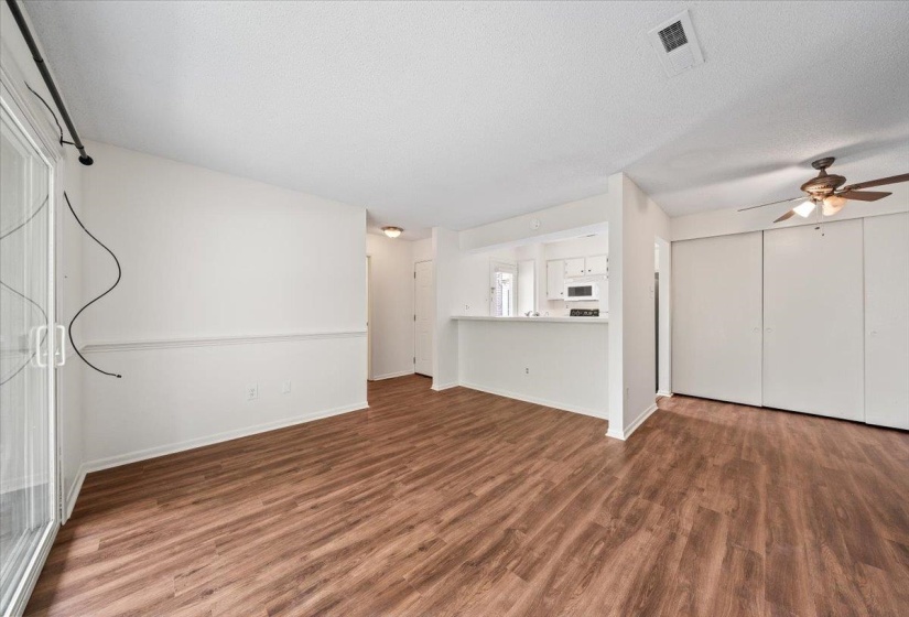 Unfurnished living room with dark wood-type flooring, ceiling fan, and a textured ceiling