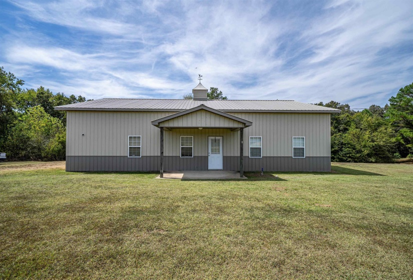 Rear view of property featuring a patio, a lawn, a metal roof, and a chimney