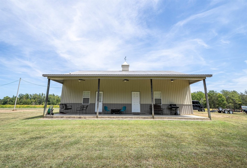 Rear view of house featuring a large porch, a lawn, and a metal roof