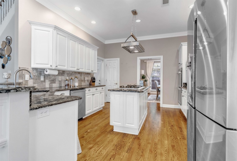 Kitchen featuring stainless steel appliances, dark stone countertops, white cabinetry, crown molding, and decorative backsplash