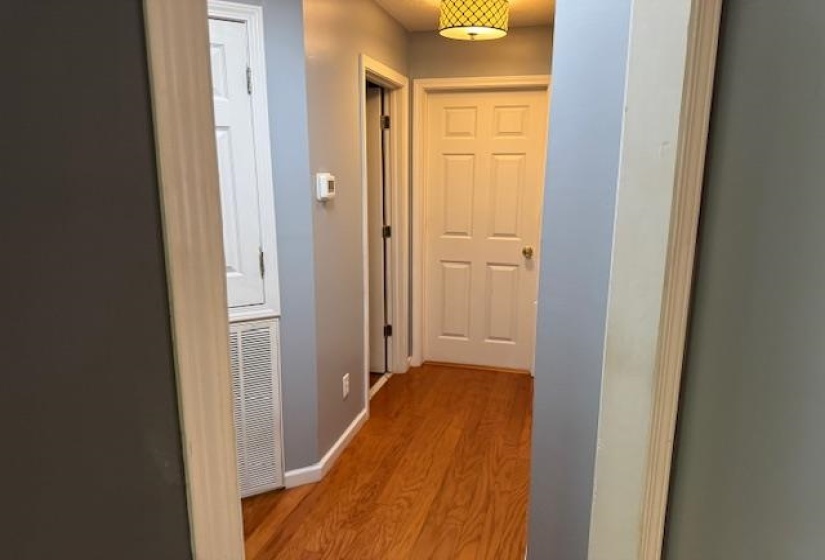 Hallway featuring wood-finish flooring, light blue wall paint, white trim, and a decorative ceiling light fixture
