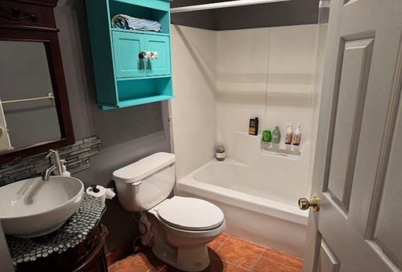Bathroom with a white bathtub and shower surround, a white toilet, and a vanity featuring a vessel sink