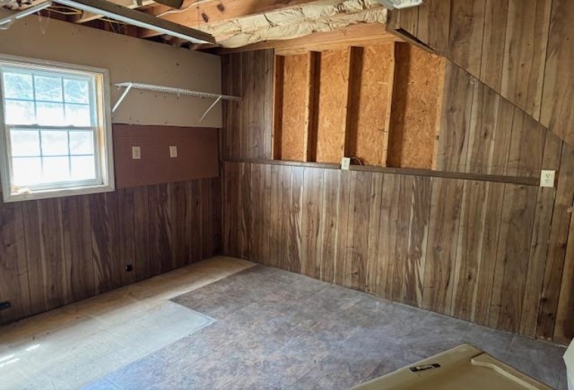 Wood-finish wall paneling, a fixed window with grid inserts, and exposed ceiling joists characterize this room