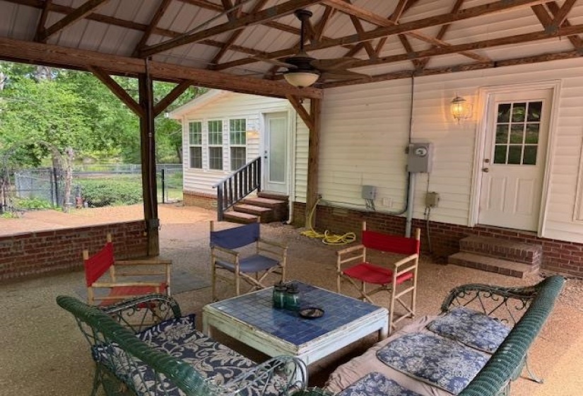 Covered outdoor living area featuring a metal roof, exposed wood beam construction, and a ceiling fan