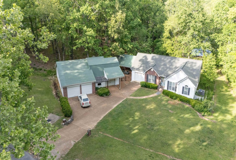 Expansive property featuring two distinct structures, a brick and siding residence with a dark roof, and a separate structure with a green metal roof