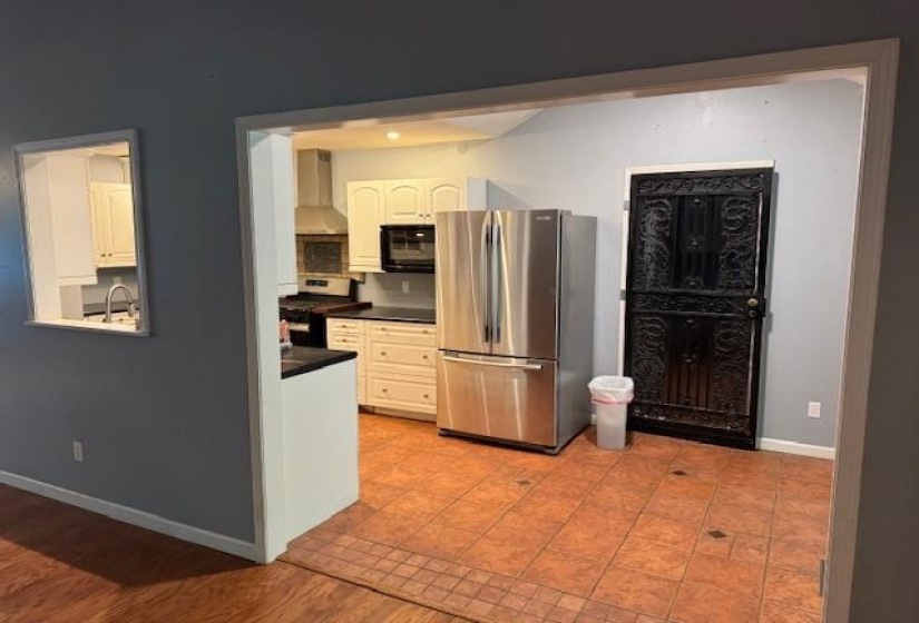 Kitchen featuring stainless steel appliances, light-toned cabinetry, and dark countertops