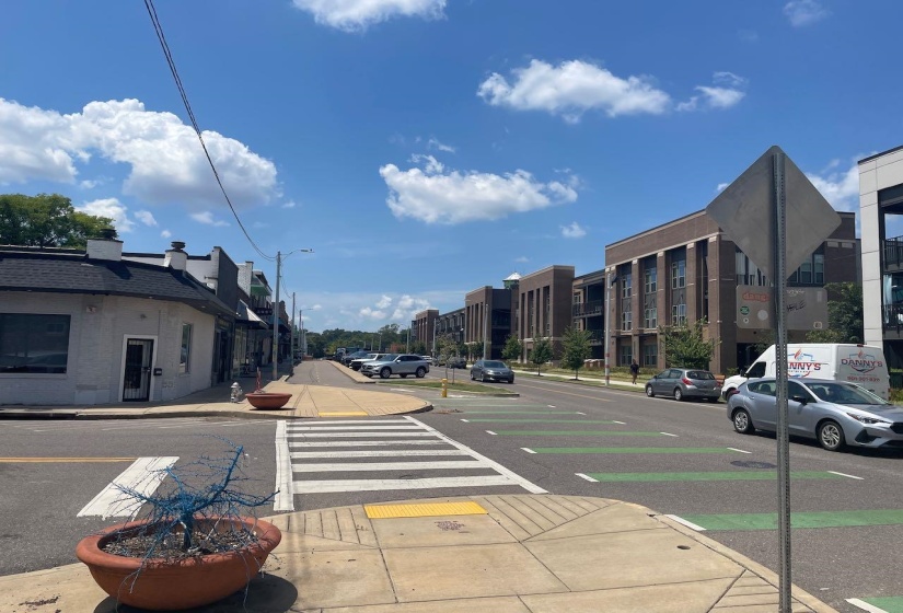 View of asphalt street with curbs, street lighting, and sidewalks