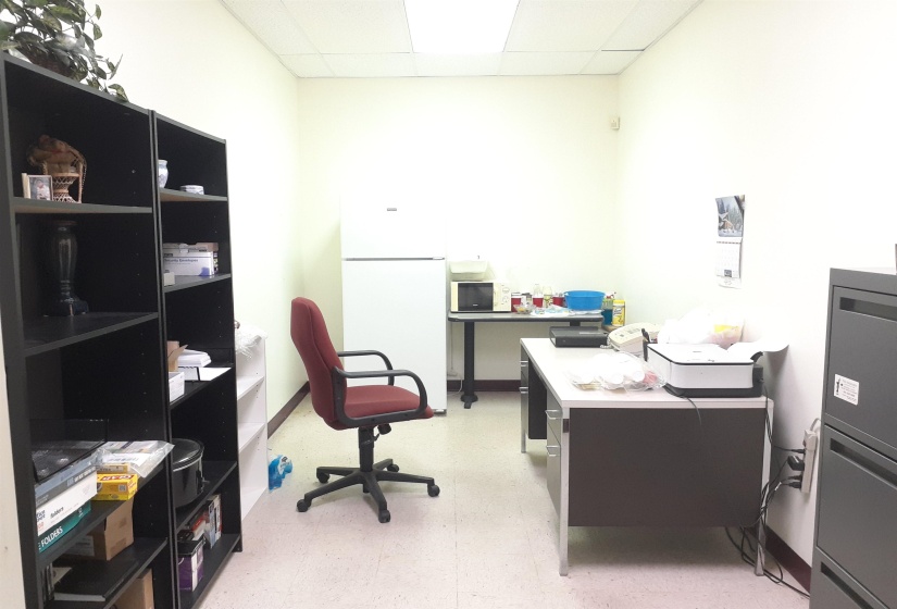 Office area featuring light floors, a drop ceiling, and heating unit