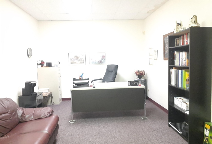 Office space featuring dark carpet and a paneled ceiling