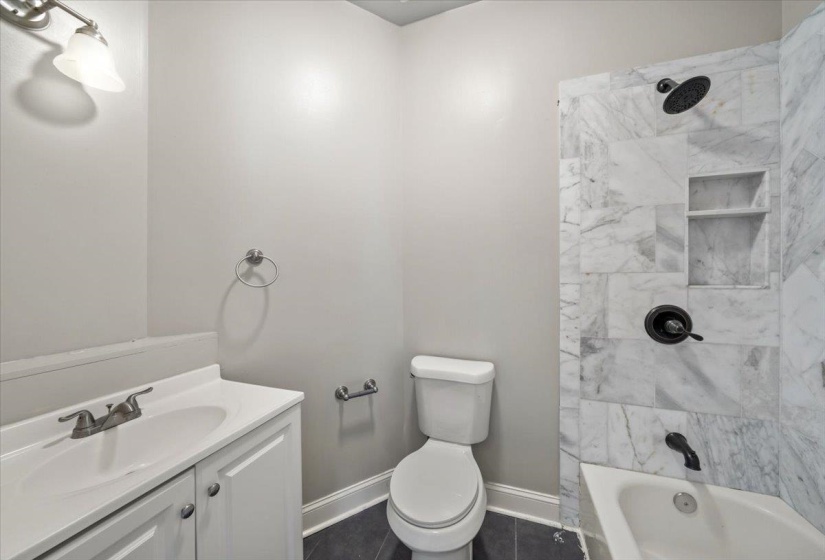 Full bathroom with vanity,  shower combination, and dark tile patterned floors