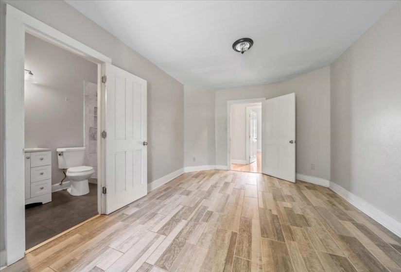 Unfurnished bedroom with wood tiled floors and ensuite bath