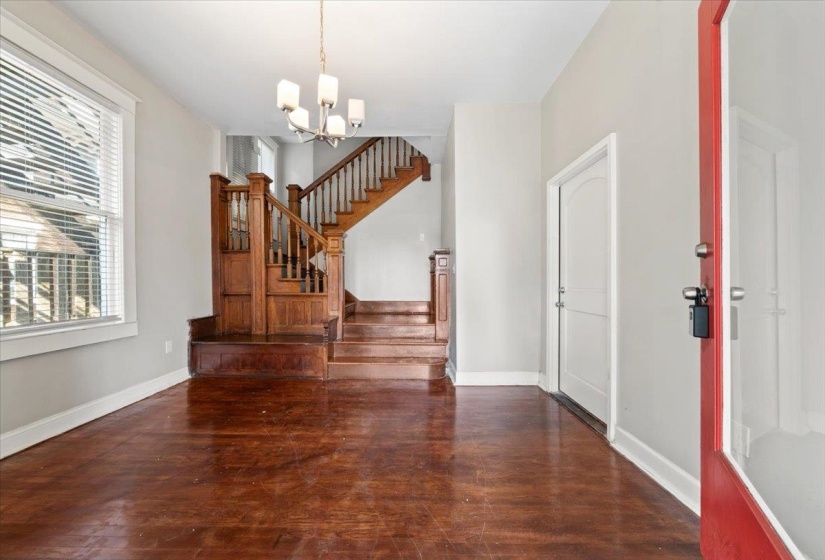 Entrance foyer with dark wood-style floors, stairway, and a chandelier