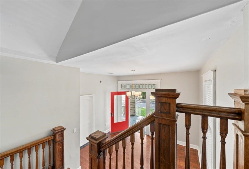 Hall with wood finished floors, a chandelier, and an upstairs landing