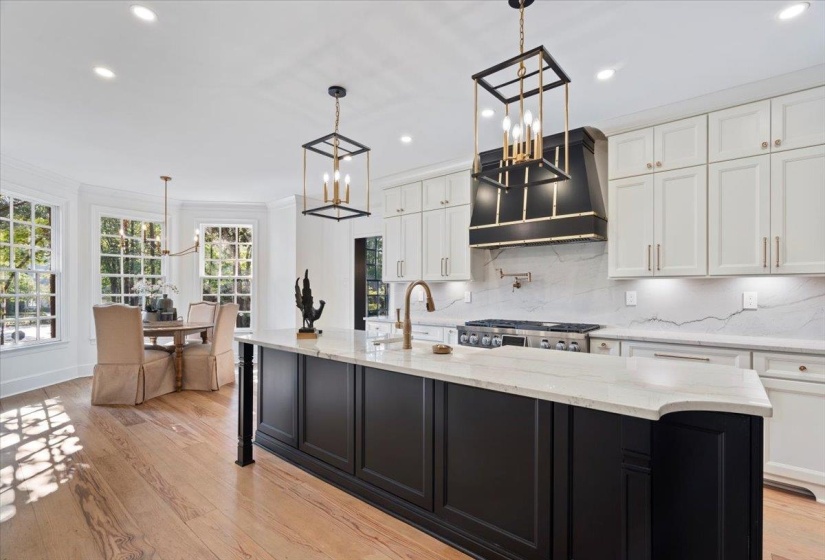 Kitchen with dark cabinets, backsplash, white cabinets, light wood-style floors, and custom exhaust hood