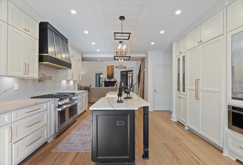Kitchen featuring decorative backsplash, light stone countertops, high quality appliances, hanging light fixtures, and white cabinetry