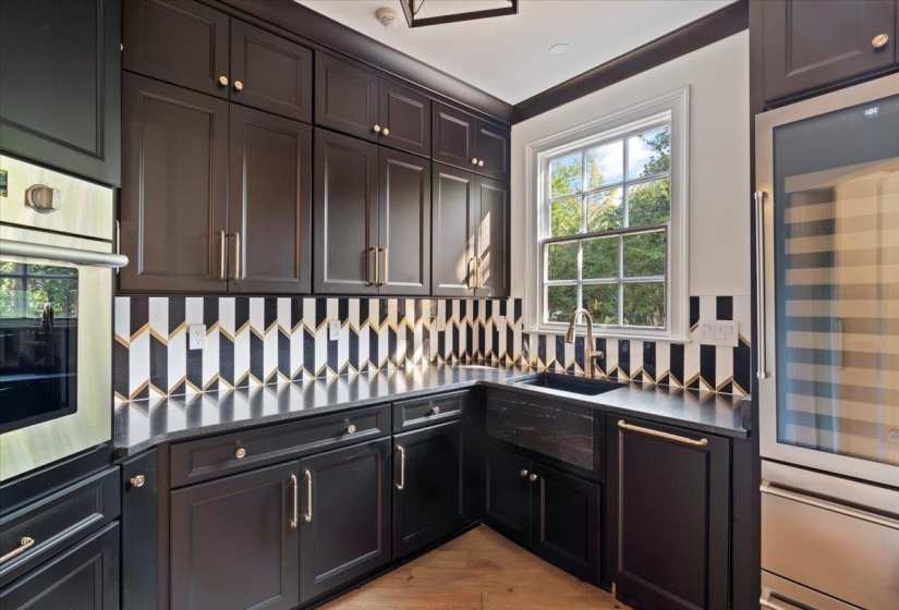Kitchen featuring beverage cooler, decorative backsplash, stainless steel oven, and light wood-style floors