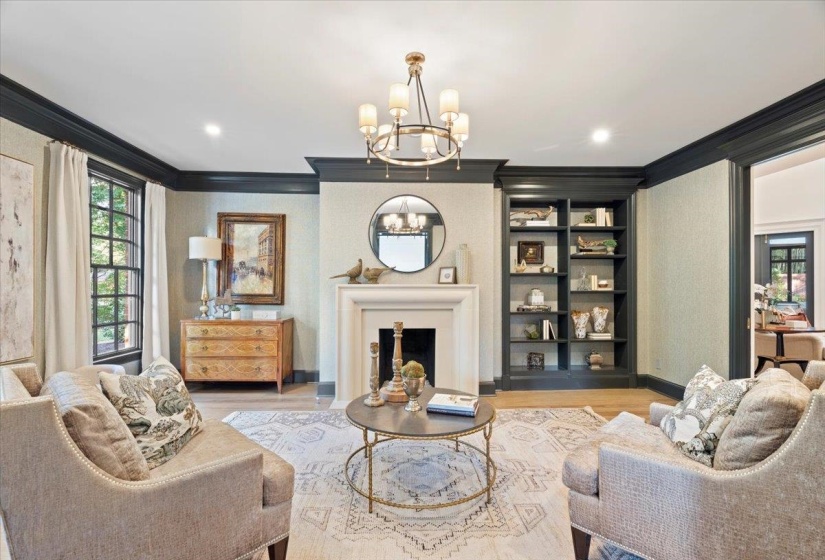 Living area with healthy amount of natural light, ornamental molding, a large fireplace, a chandelier, and wood finished floors