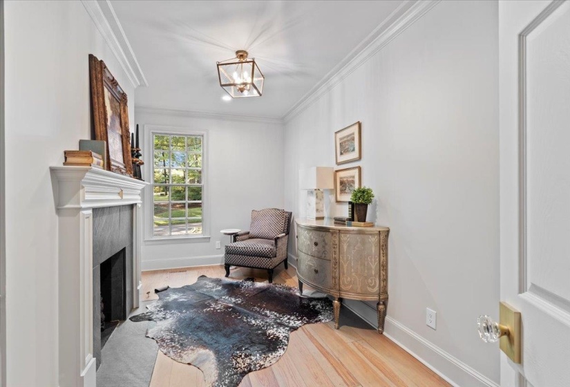 Sitting room with ornamental molding, light wood finished floors, a fireplace, and a chandelier