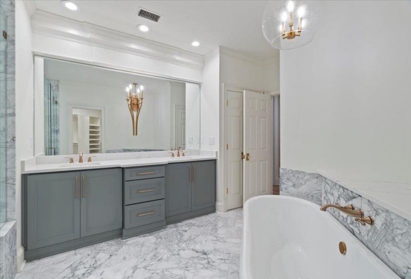 Full bath with a freestanding bath, double vanity, crown molding, a chandelier, and a closet